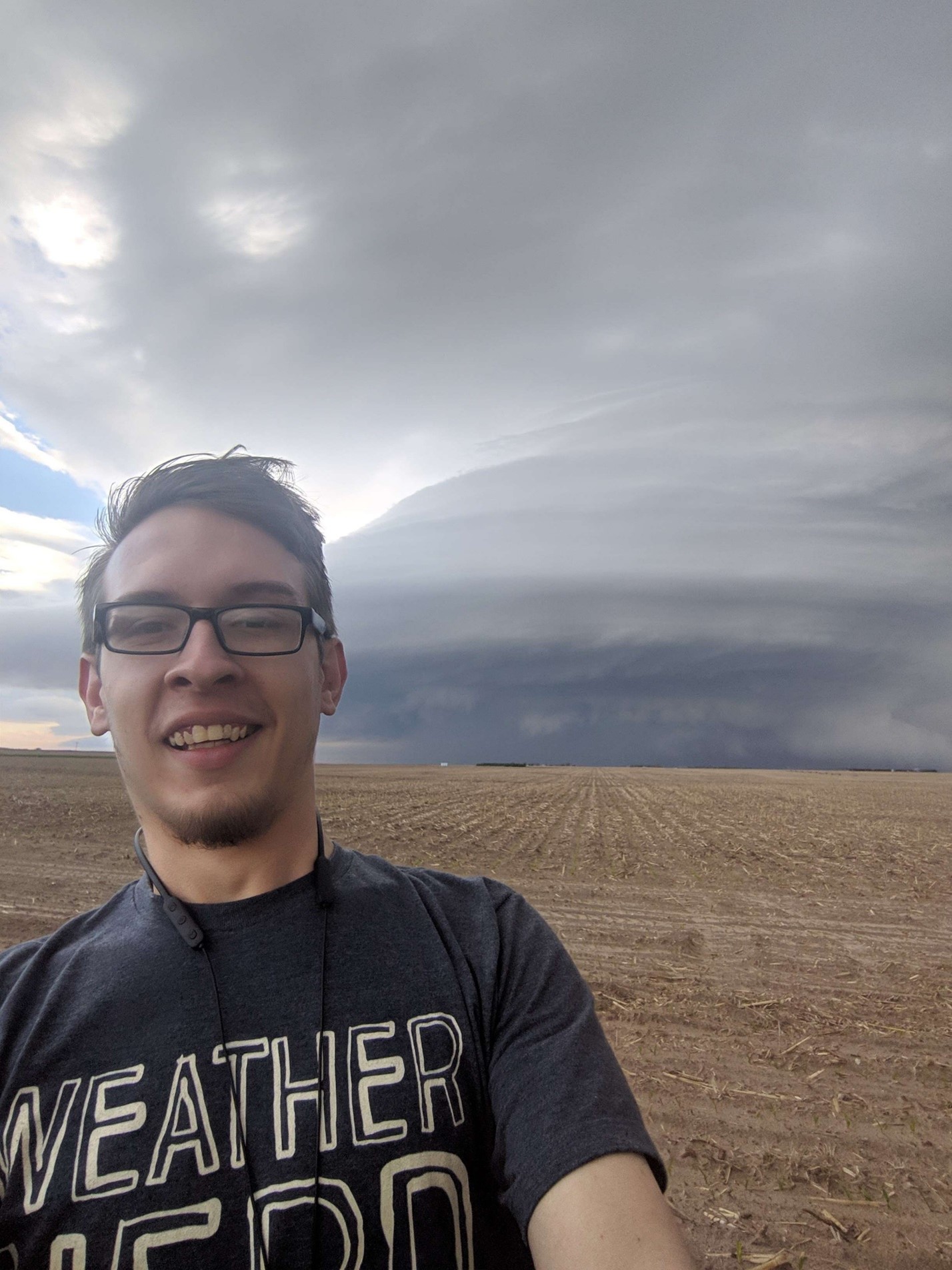 Skyview Weather Meteorologist Aaron O'Brien taking a selfie in front of a supercell thunderstorm while standing in a field.