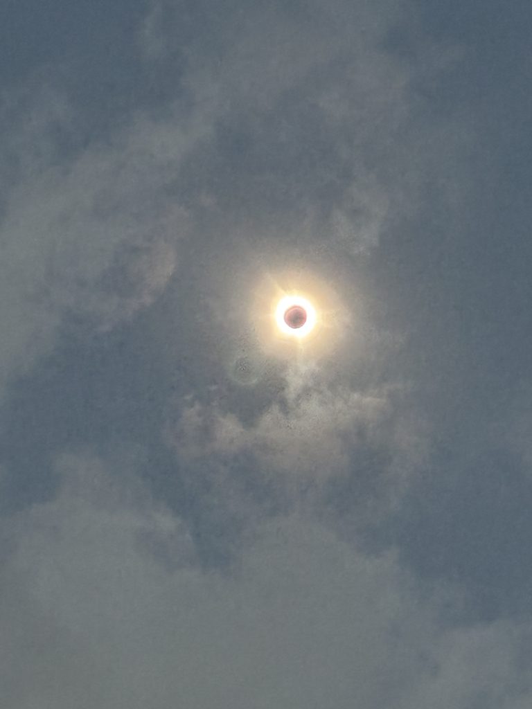 Image taken by Meteorologist Shannon Holland, depicting the total solar eclipse in Dallas, Texas. The sky surrounding the eclipsed sun appears significantly darker, resembling the twilight hues of dusk or dawn. This captivating moment of totality offers a rare glimpse into the cosmic dance of celestial bodies.