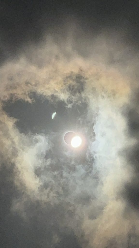 Image depicting the moment just after totality during a solar eclipse, where the "diamond ring" effect is visible. On the left side of the image, the ethereal corona of the sun is clearly visible against the darkened sky. On the right side, the sun emerges from behind the moon, creating a dazzling burst of light resembling a diamond ring. This captivating celestial event was captured with precision by Meteorologist Shannon Holland.