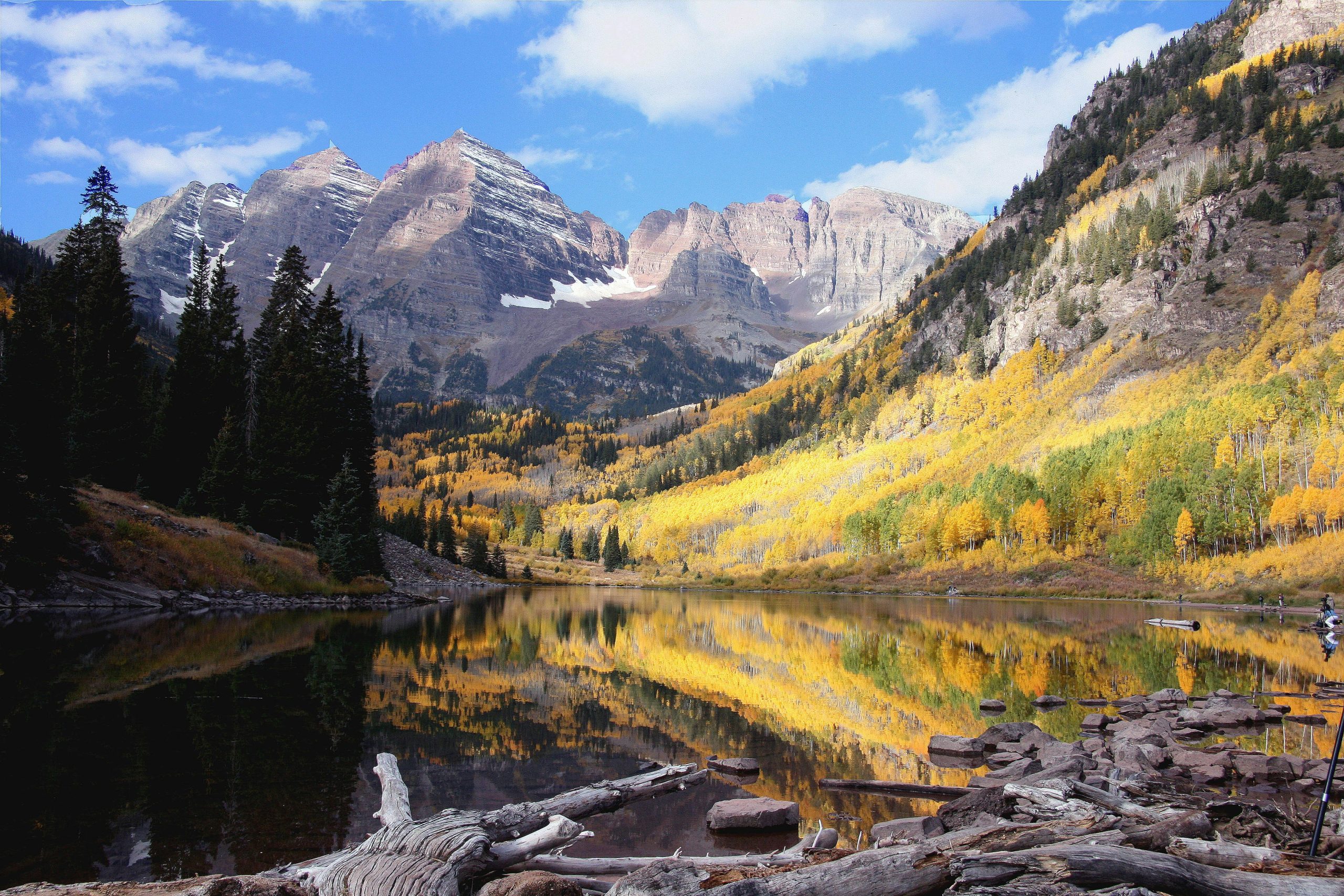A photograph of Maroon Bells, Colorado, behind aspen trees changing colors during fall.