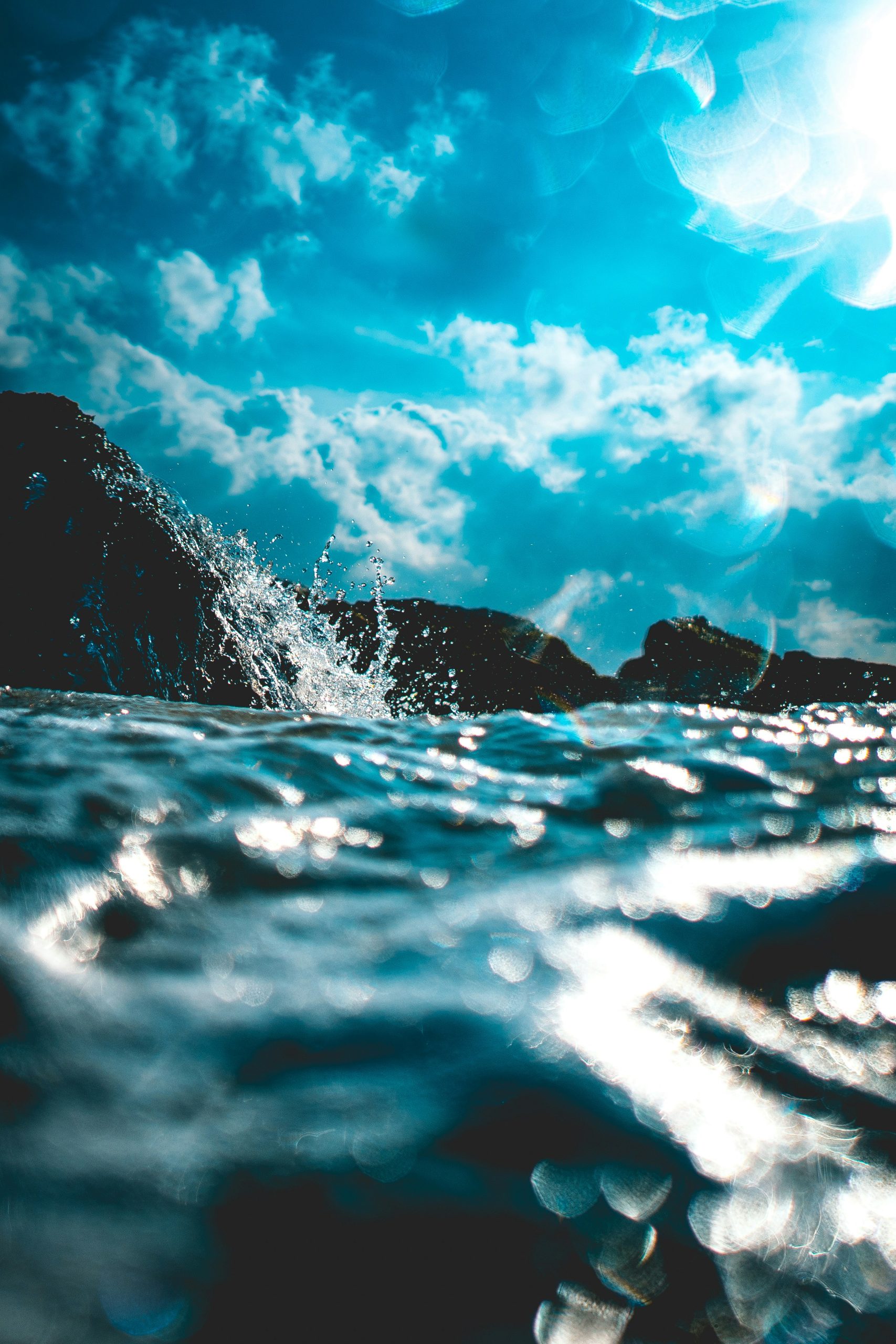 A photograph of water splashing against rocks on a sunny day.