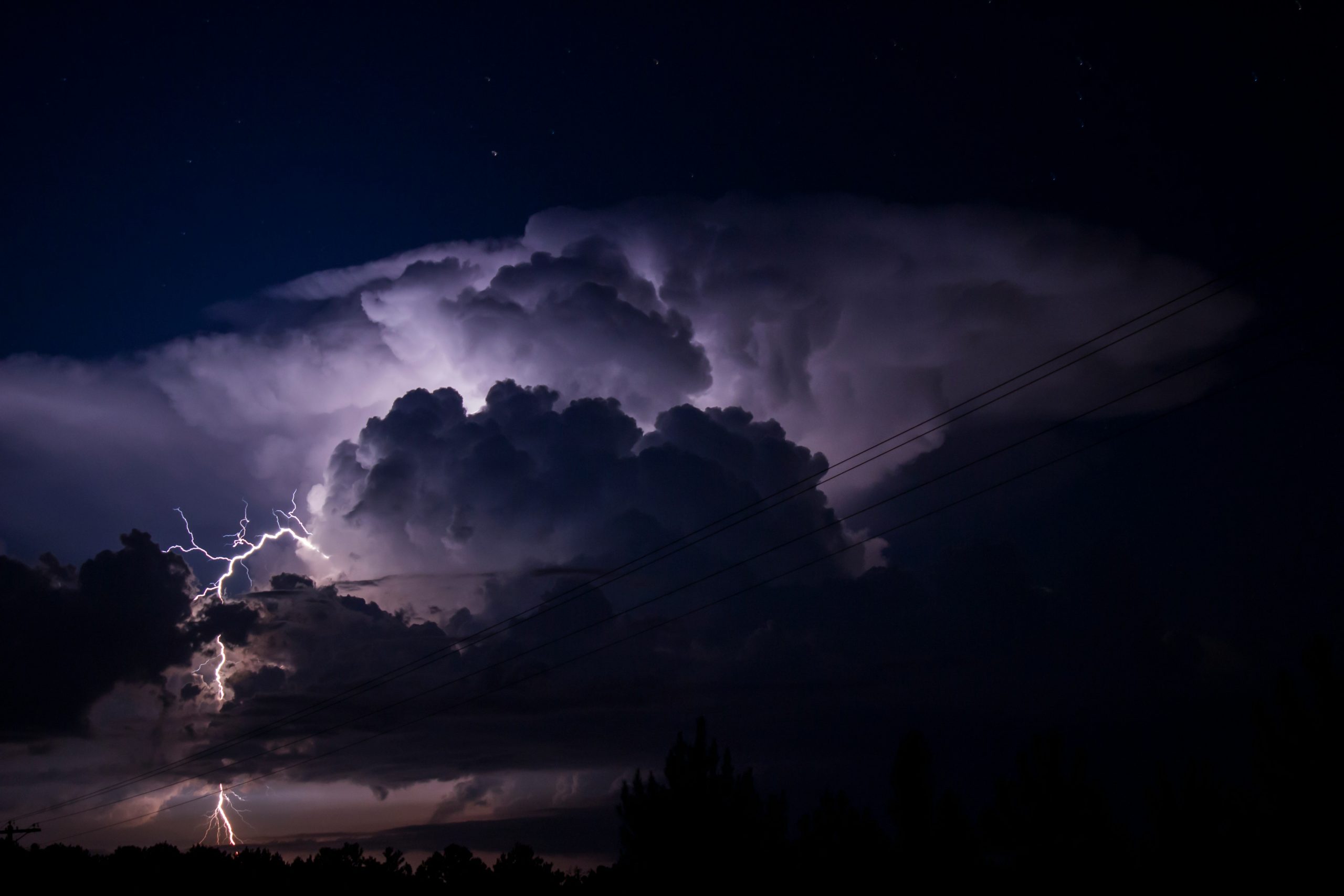 A photograph of a thunderstorm with lightning at night.